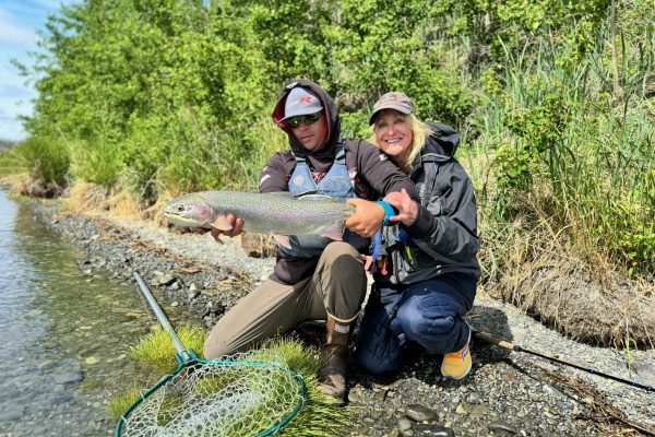 Guide with client holding rainbow trout on the Kenai River in June